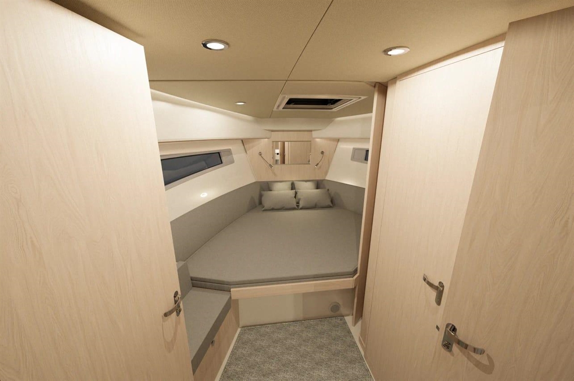 Cozy boat cabin featuring a round bed with gray cushions, wood paneling, and dual doors, illuminated by ceiling lights.